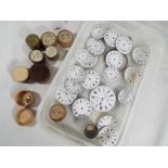 A collection of enameled pocket watch faces and various other watch parts