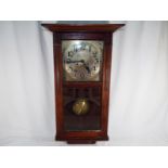 A mahogany wall clock with Arabic numerals on a brass fascia with pendulum