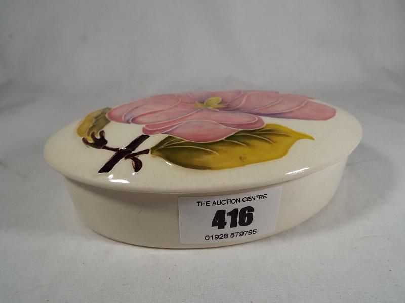 A Moorcroft Pottery lidded oval trinket box decorated with pink magnolia on an ivorine ground, 3.