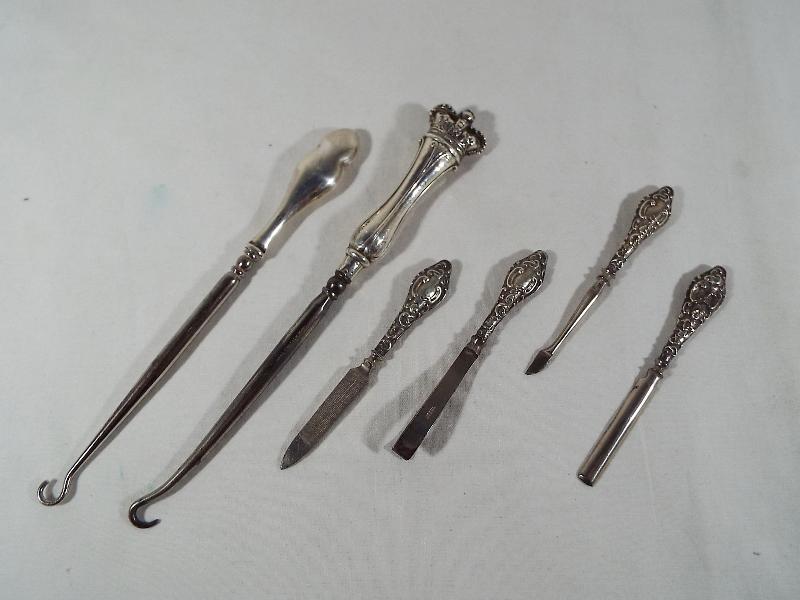 Two silver handled button hooks one with handle in the form of a crown and a four piece manicure