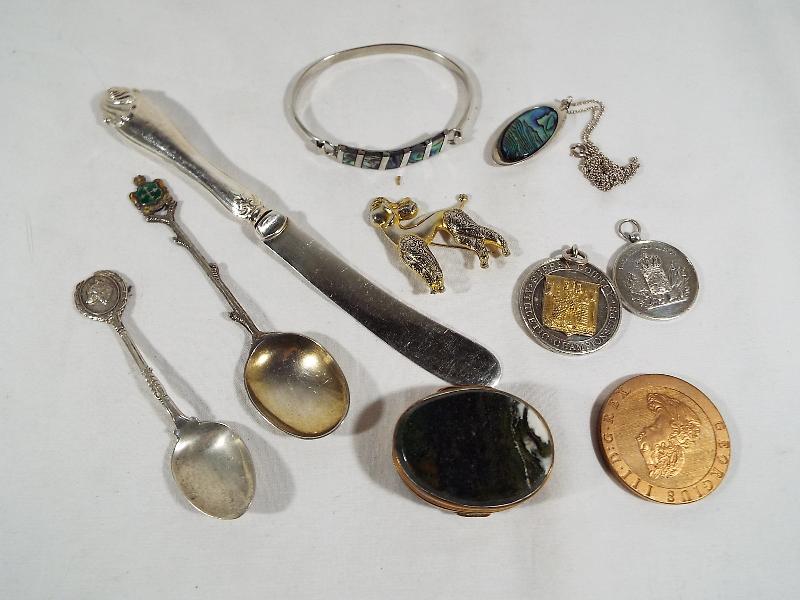 A mixed lot to include silver hallmarked tea spoons, white metal medallions, pendant, pill box,