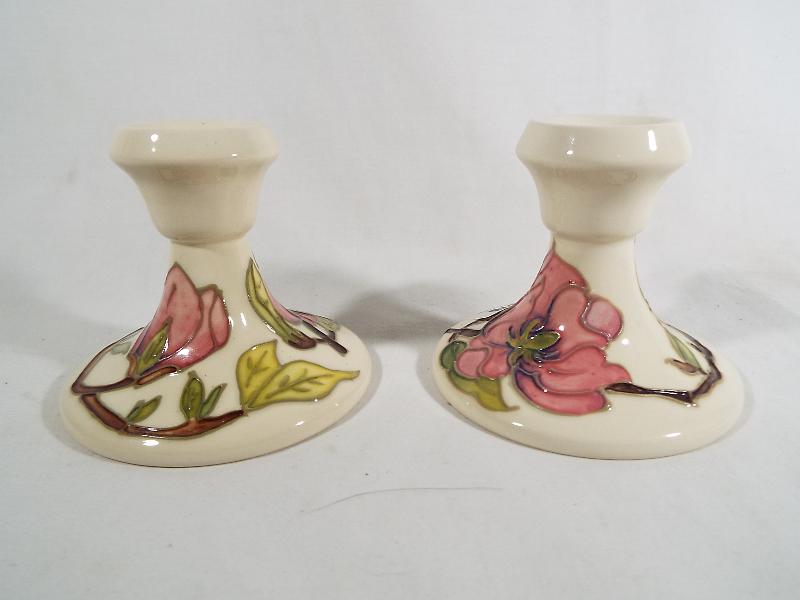 A Moorcroft Pottery pair of candlesticks decorated with pink magnolia on an ivorine ground,