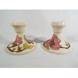 A Moorcroft Pottery pair of candlesticks decorated with pink magnolia on an ivorine ground,