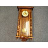 A wall mounted Vienna style clock in a walnut veneer case flanked by turned columns and finial's,