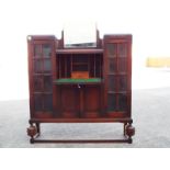 A writing bureau flanked by two glass fronted cabinets with covered space below