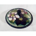 A Moorcroft Pottery lidded powder bowl decorated in the green clematis pattern, signed to the base,