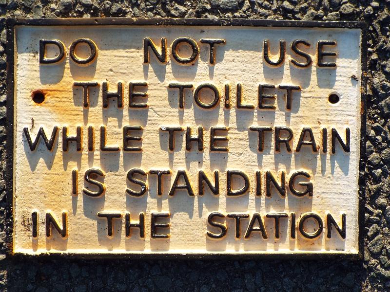 A cast iron sign marked 'Do not use the toilet while the train is standing in the station' 19 cm x