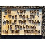 A cast iron sign marked 'Do not use the toilet while the train is standing in the station' 19 cm x