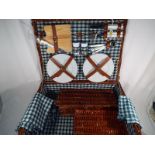 A good quality wicker picnic basket containing a 4 place setting to include ceramic plates, mugs,