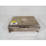 A silver plated cigar / cigarette box, engine turned decoration supported on four feet,