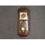 A wall mounted Vienna style clock in a walnut veneer case flanked by turned columns and finial's,