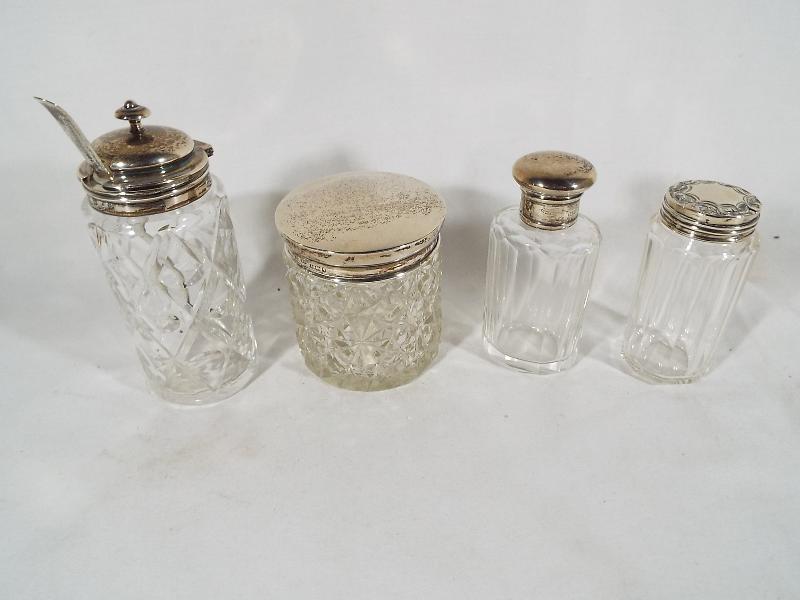 Four glass jars, all with hallmarked silver caps / mounts,