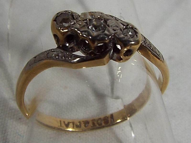 An 18ct gold and platinum three stone diamond cross over ring, set with old cut diamonds, size I1/2,