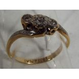 An 18ct gold and platinum three stone diamond cross over ring, set with old cut diamonds, size I1/2,