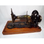 An early 20th century Singer sewing machine in hood case, serial number 7688377 / 1950977,