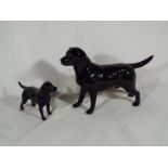 Two Beswick figurines depicting a black labradors,