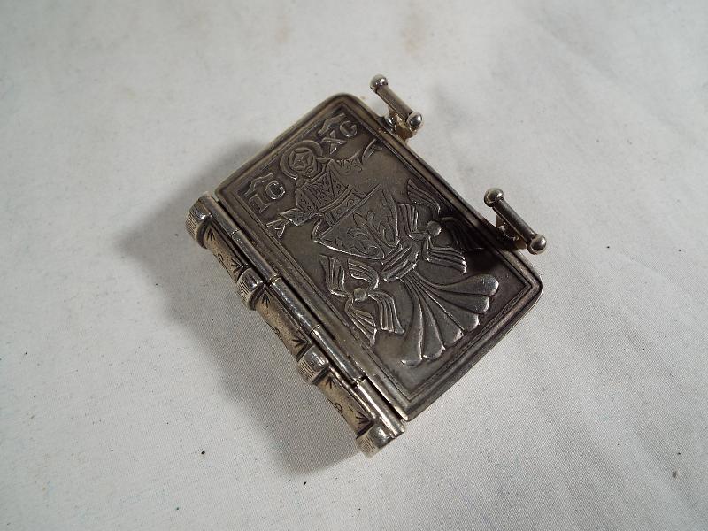 A silver vesta in the form of a miniature book with twin-internal compartments .800