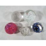 A collection of four glass domed paper weights and one heart shaped trinket dish to include