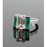 An Impressive Diamond and Emerald Ring. The central Emerald cut Diamond 3.60 carats. Colour