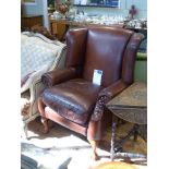 Pair of Thomas Lloyd studded brown leather wing fireside chairs on ball and claw legs