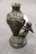 A bronze vase mounted with a cherub, on