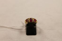 An 18ct gold three stone ruby and diamond ring. CONDITION REPORT: Good condition.