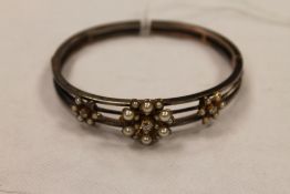 A diamond and pearl cluster bangle. CONDITION REPORT: Missing two small split pearls, the clasp
