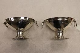 A pair of eighteenth century silver dishes, each with twin loop handles and raised upon an oval