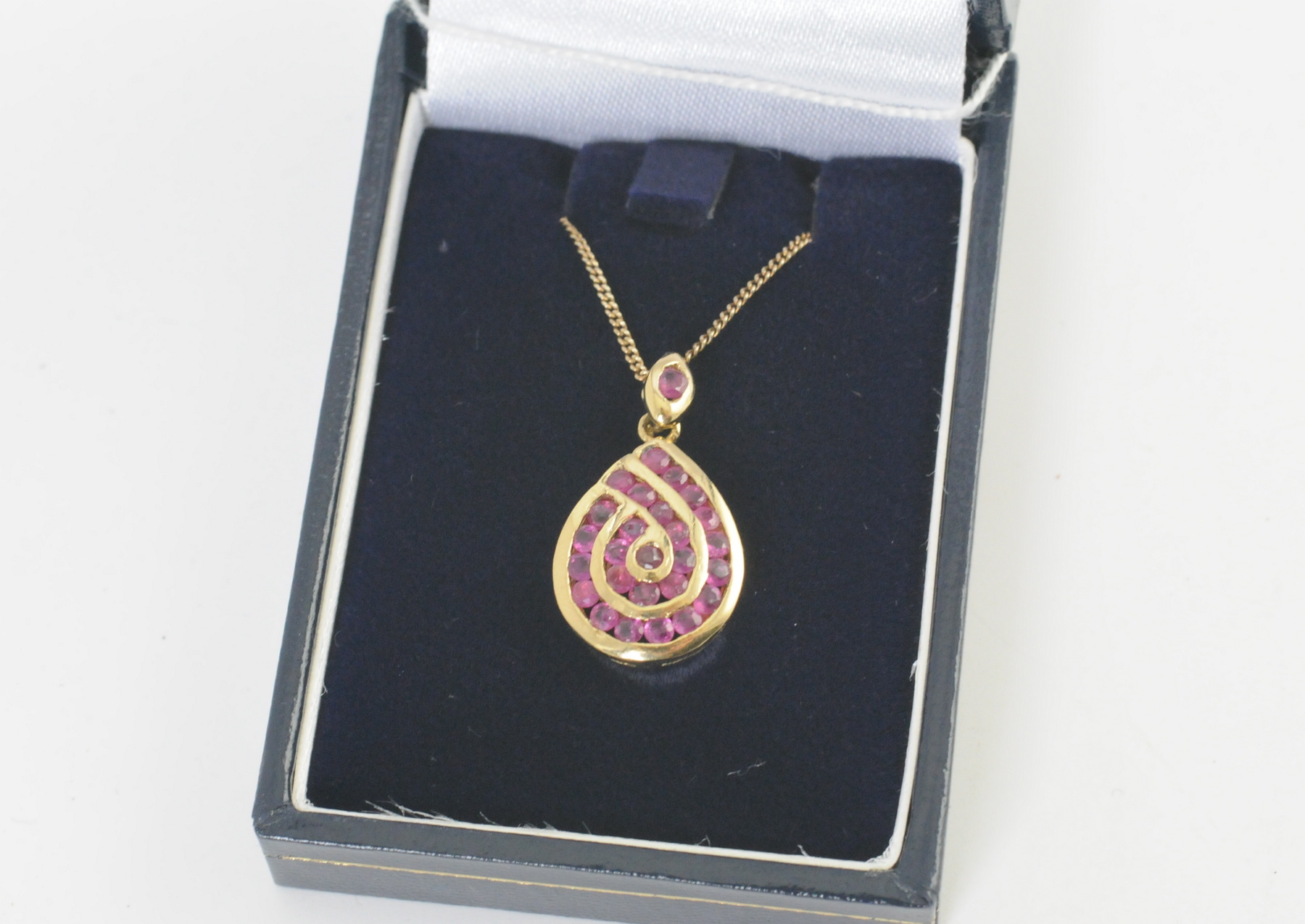 Gold pendant of pear shape with a swirli