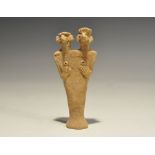 "1180-700 BC. A flat-backed ceramic figurine depicting a female with two heads; the eyes and breasts