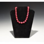 20th century AD. Designer necklace of pink dyed faceted spherical gemstone beads with gilt disc