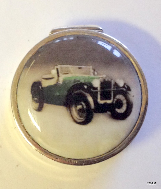 A silver and enamel pill box depicting a classic car