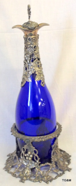 A Bristol blue decanter in a silver plated holder with grape and vine decoration