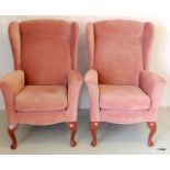 A pair of dusky pink upholstered wing back arm chairs