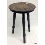 An ebonised carved topped milking stool 36cm high
