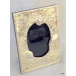 A decorative embossed silver mirror on easel back
