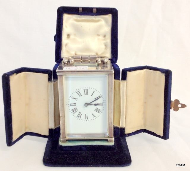 A silver case carriage clock with enamel face and original velvet case