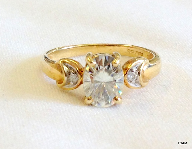 A gold ring set a large oval Moissanite (tests as a diamond) with diamond shoulders