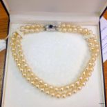 A double pearl necklace with white and blue stones on the clasp