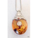 A large amber pendant with white metal mounts and chain