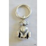 A silver teething ring with a bear attached