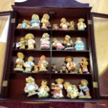 A collection of Cherished Teddies in a wall display cabinet