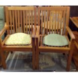 A pair of teak garden arm chairs