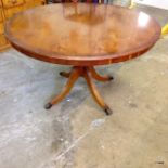 A circular teak table on clawed brass castors 75 x 125cm