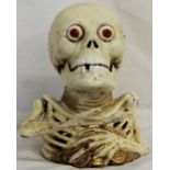 A cast metal money box in the form of a skeleton