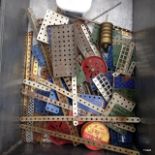 Metal box containing vintage mecano parts, including pullies.