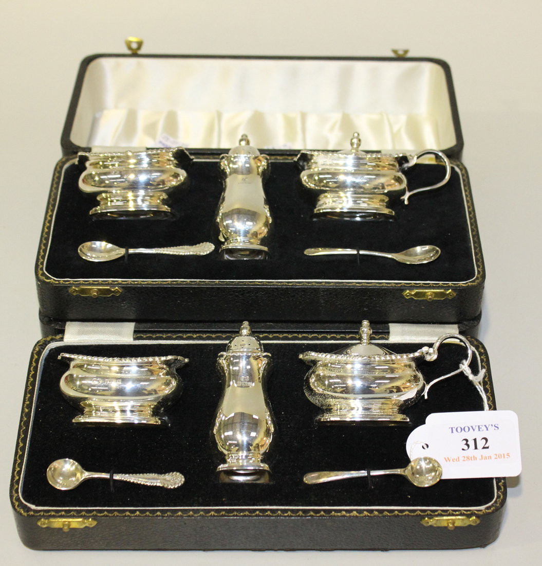 Two three piece silver condiment sets, each of rectangular form with gadrooned and scallop shell