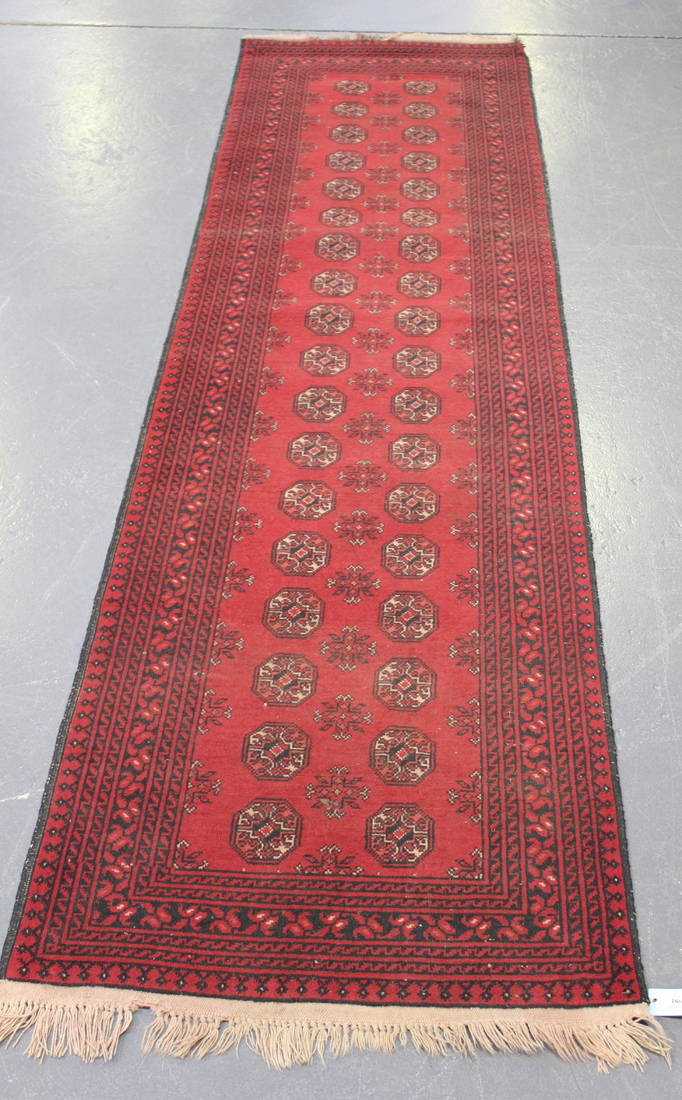 An Afghan runner, mid-20th Century, the red field with two columns of guls, within a boteh border,