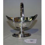 An Edwardian silver bonbon basket of oval lobed form with reeded rim and swing handle, on an oval