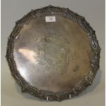 An Edwardian silver circular salver, engraved with a scroll cartouche within an embossed floral